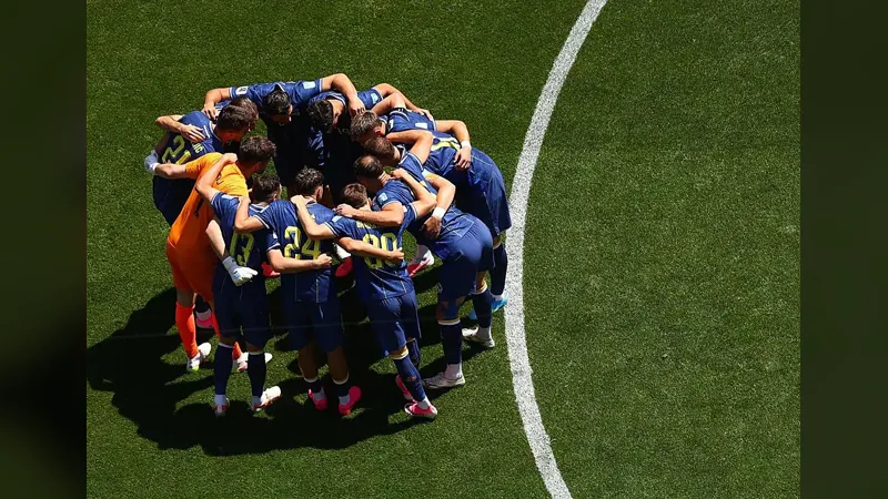 A youth football team in a huddle on the pitch, seen from above