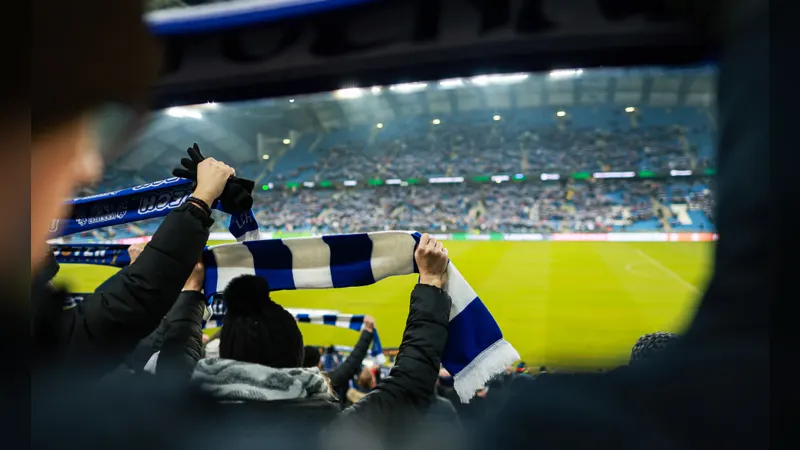 Football fans in a stand holding scarves above their heads