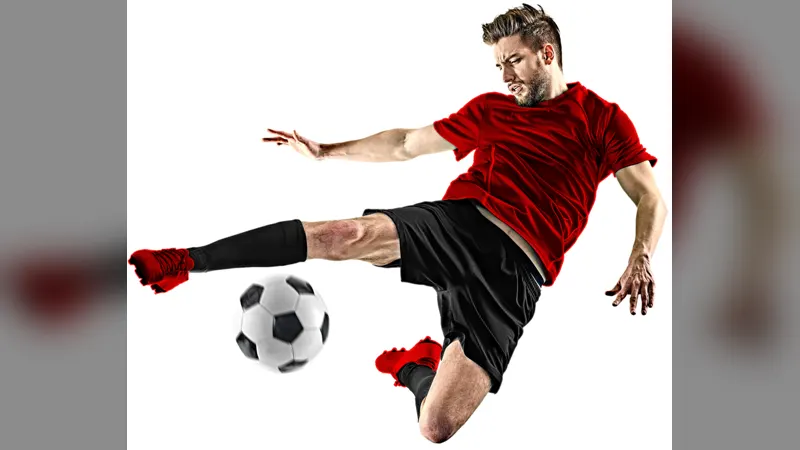 A footballer in a red shirt volleying a ball against a white background