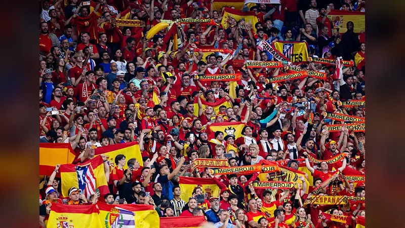 Spain football fans in red filling a stadium stand with flags