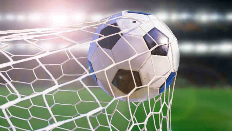 A football bursting into the back of a goal net